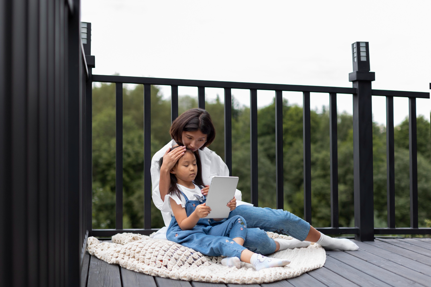 Mother and child spending quality time together on outdoor home decking with greenery behind, by Superior Decking Australia. 